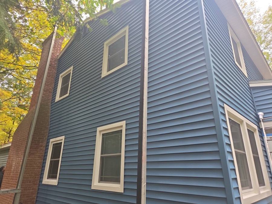 A completed two-storey exterior corner finished in vivid blue horizontal lap siding, with crisp white-trimmed windows.
